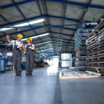 factory-workers-work-wear-yellow-helmets-walking-through-industrial-production-hall-sharing-ideas-about-organization-1